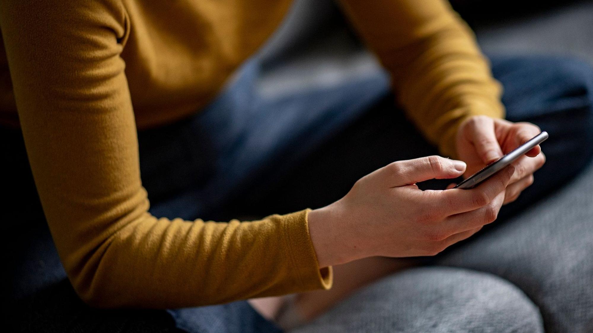 Eine 15-Jährige wurde mit Bildern erpresst und im Internet vorgeführt. Sie nahm sich das Leben. Unser Symbolfoto zeigt eine junge Frau mit ihrem Smartphone in der Hand.