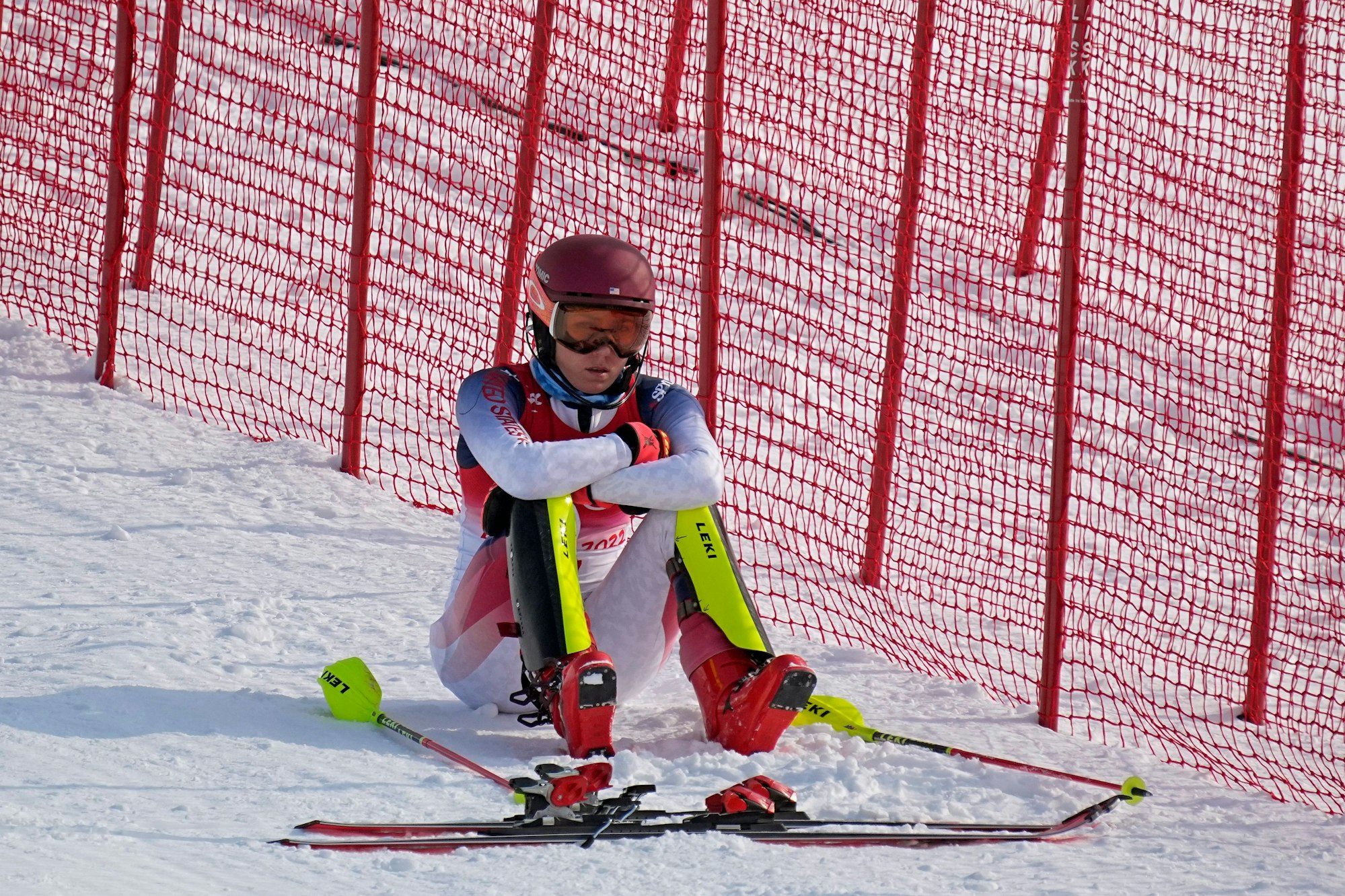 Mikaela Shiffrin sitzt nach ihrem Slalom-Aus frustriert im olympischen Schnee.