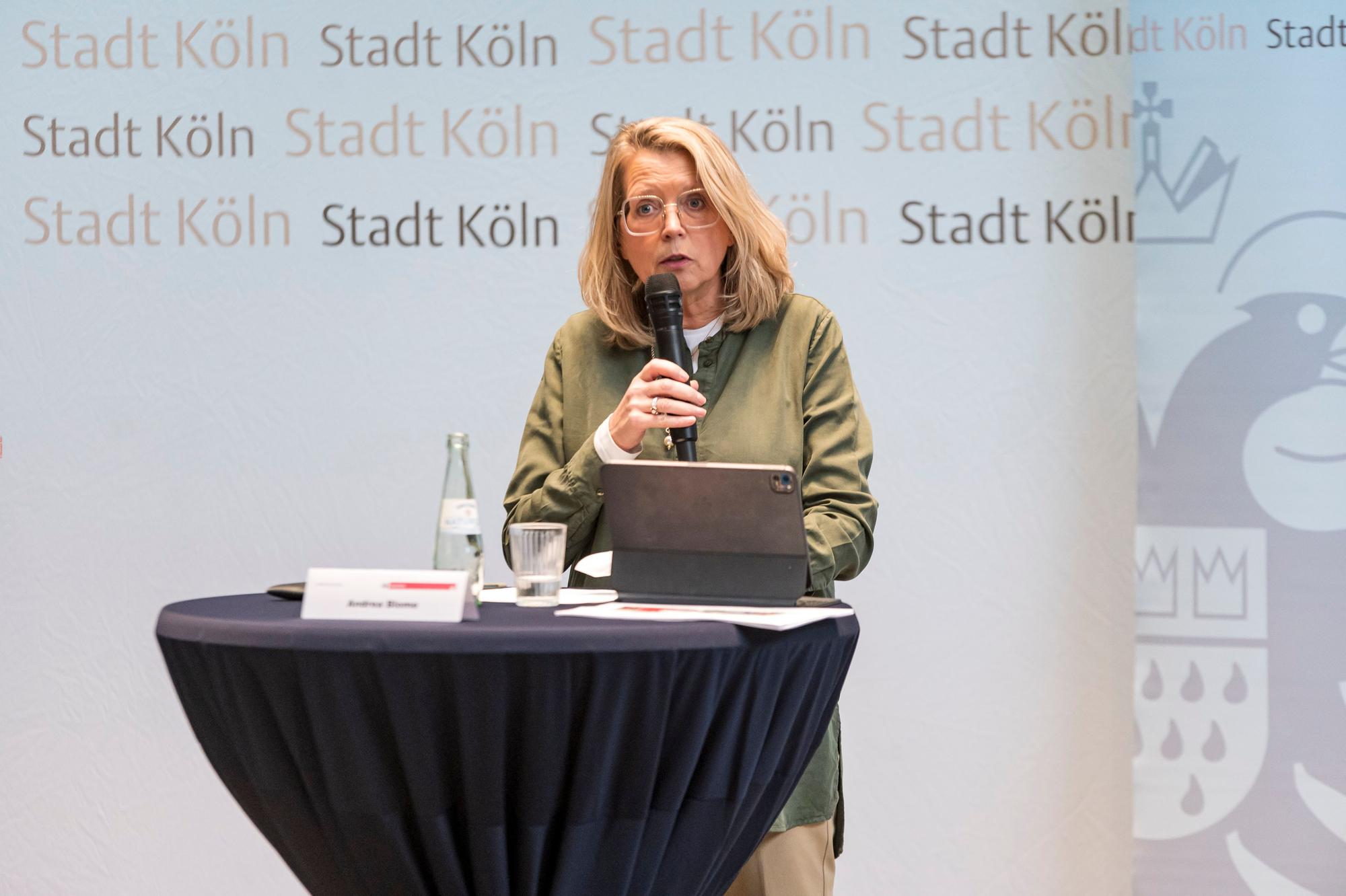 Stadtdirektorin Andrea Blome redet auf einer PK mit Mikrofon.