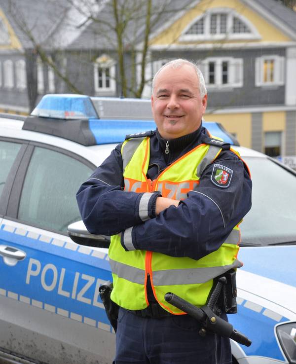 Polizist Rolf Stangenberg
vor einem Polizei-Auto.