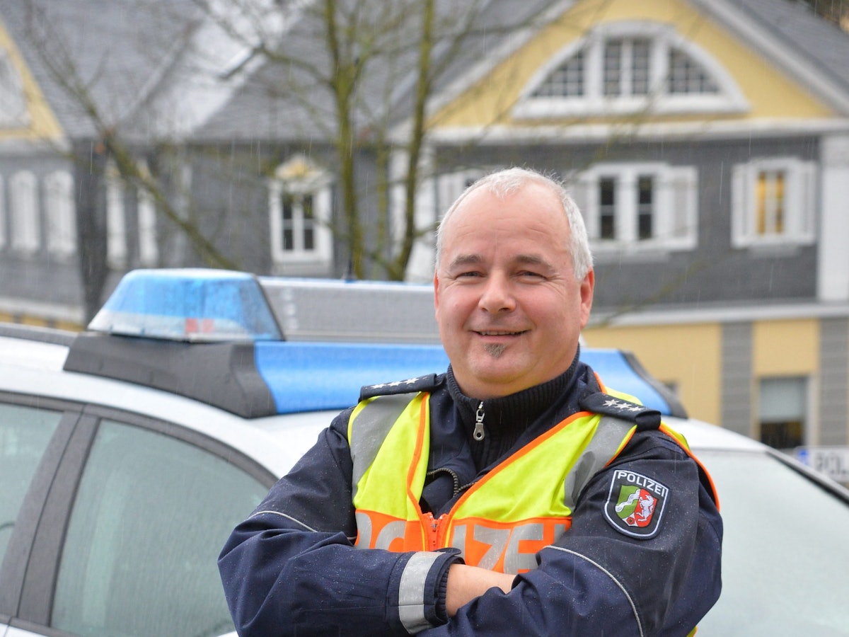 Polizist Rolf Stangenberg
vor einem Polizei-Auto.