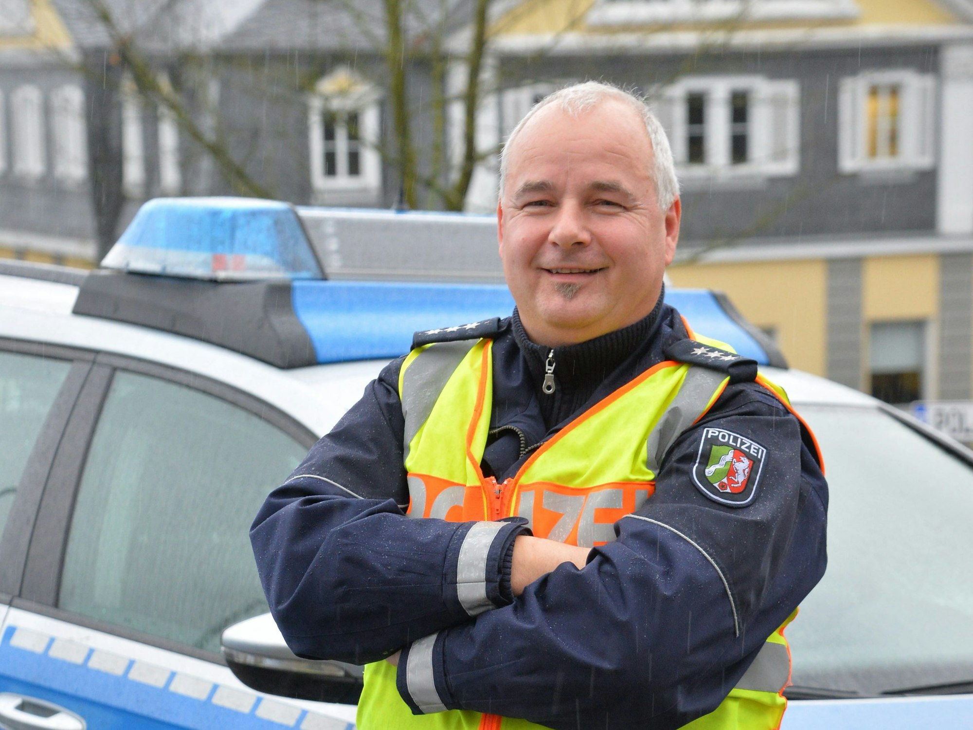 Polizist Rolf Stangenberg 
vor einem Polizei-Auto.