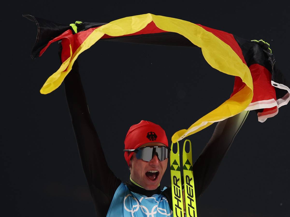 Vinzenz Geiger jubelt mit Deutschland-Fahne bei Olympia in China.