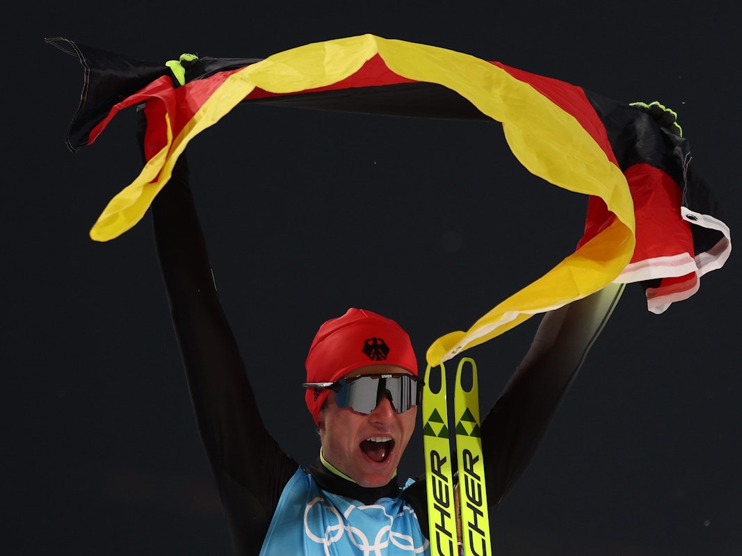 Vinzenz Geiger jubelt mit Deutschland-Fahne bei Olympia in China.