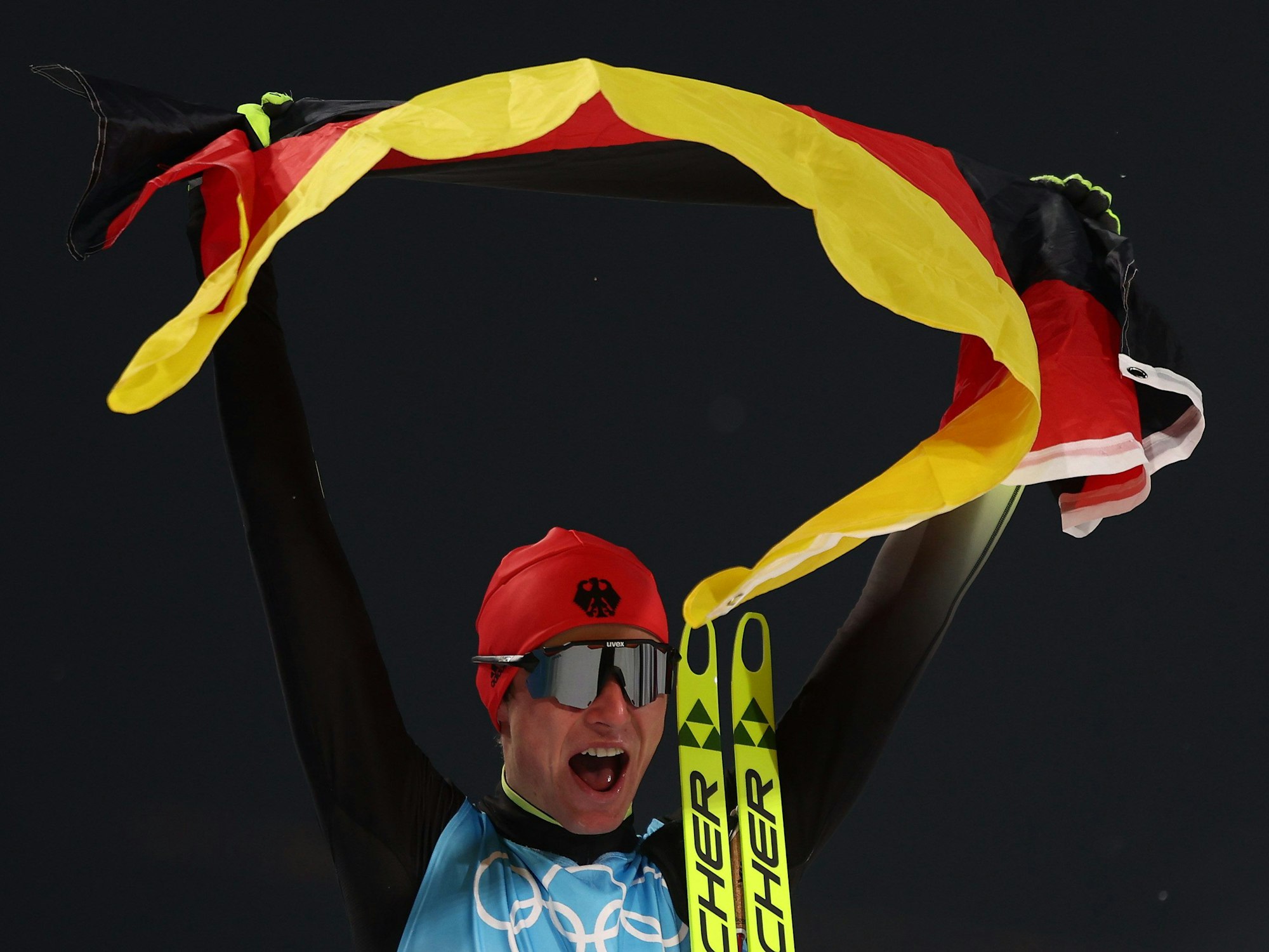 Vinzenz Geiger jubelt mit Deutschland-Fahne bei Olympia in China.