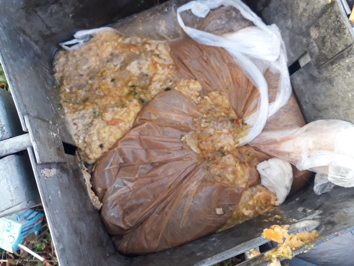 In einem Papierkorb liegt ein aufgeplatzter Beutel mit Essensresten.