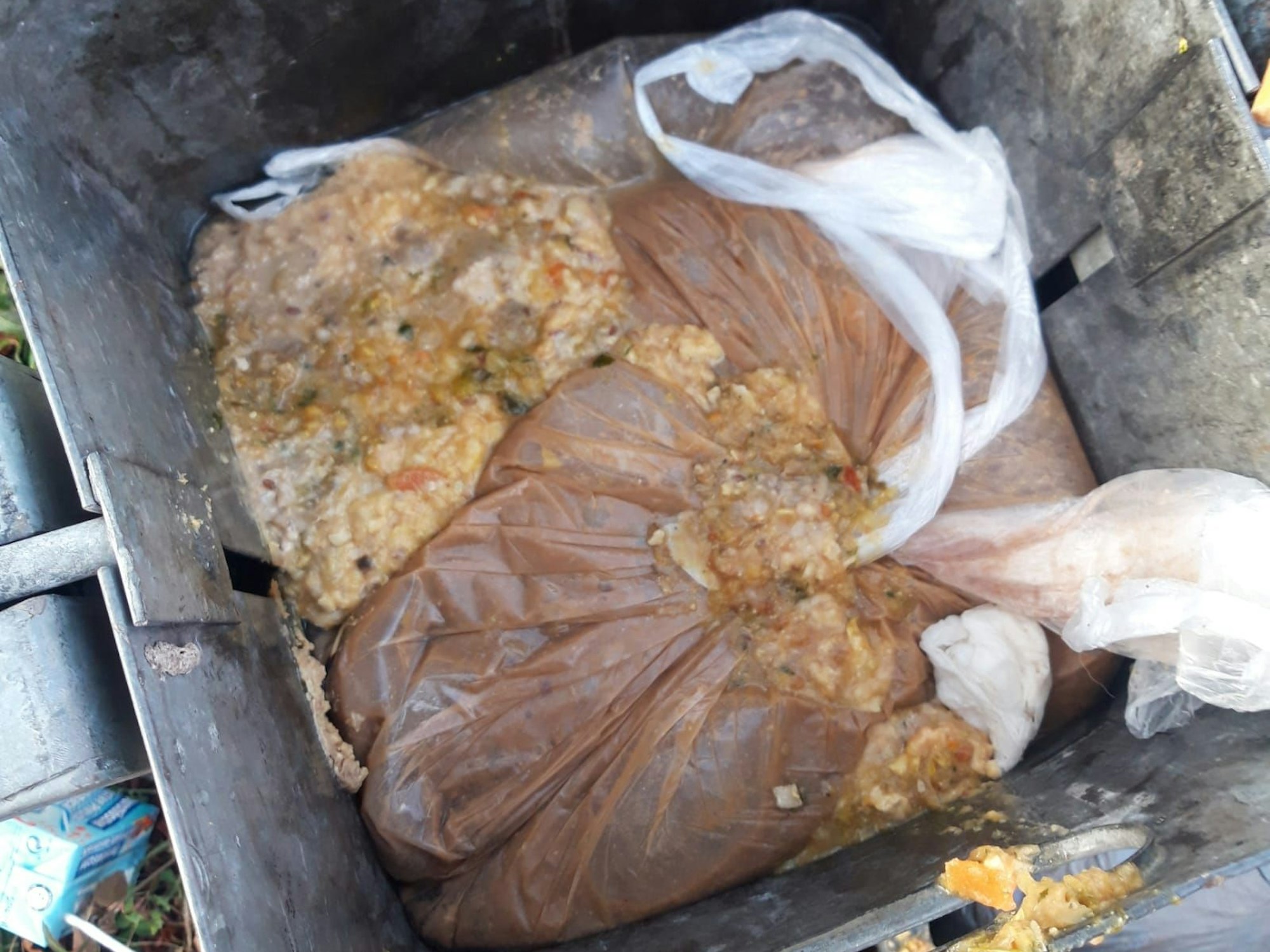 In einem Papierkorb liegt ein aufgeplatzter Beutel mit Essensresten.