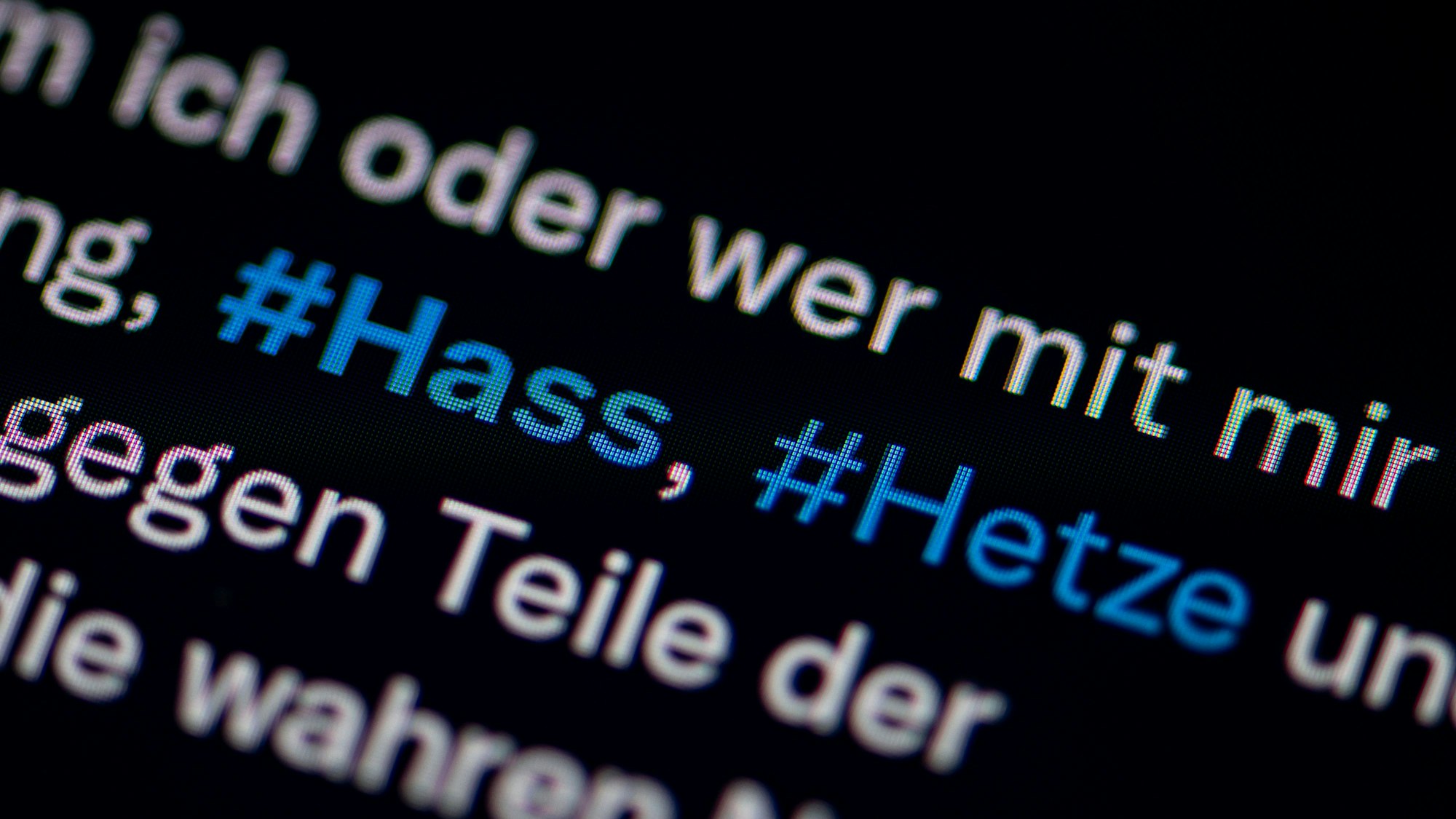 Auf dem Bildschirm eines Smartphones sieht man die Hashtags Hass und Hetze in einem Twitter-Post.