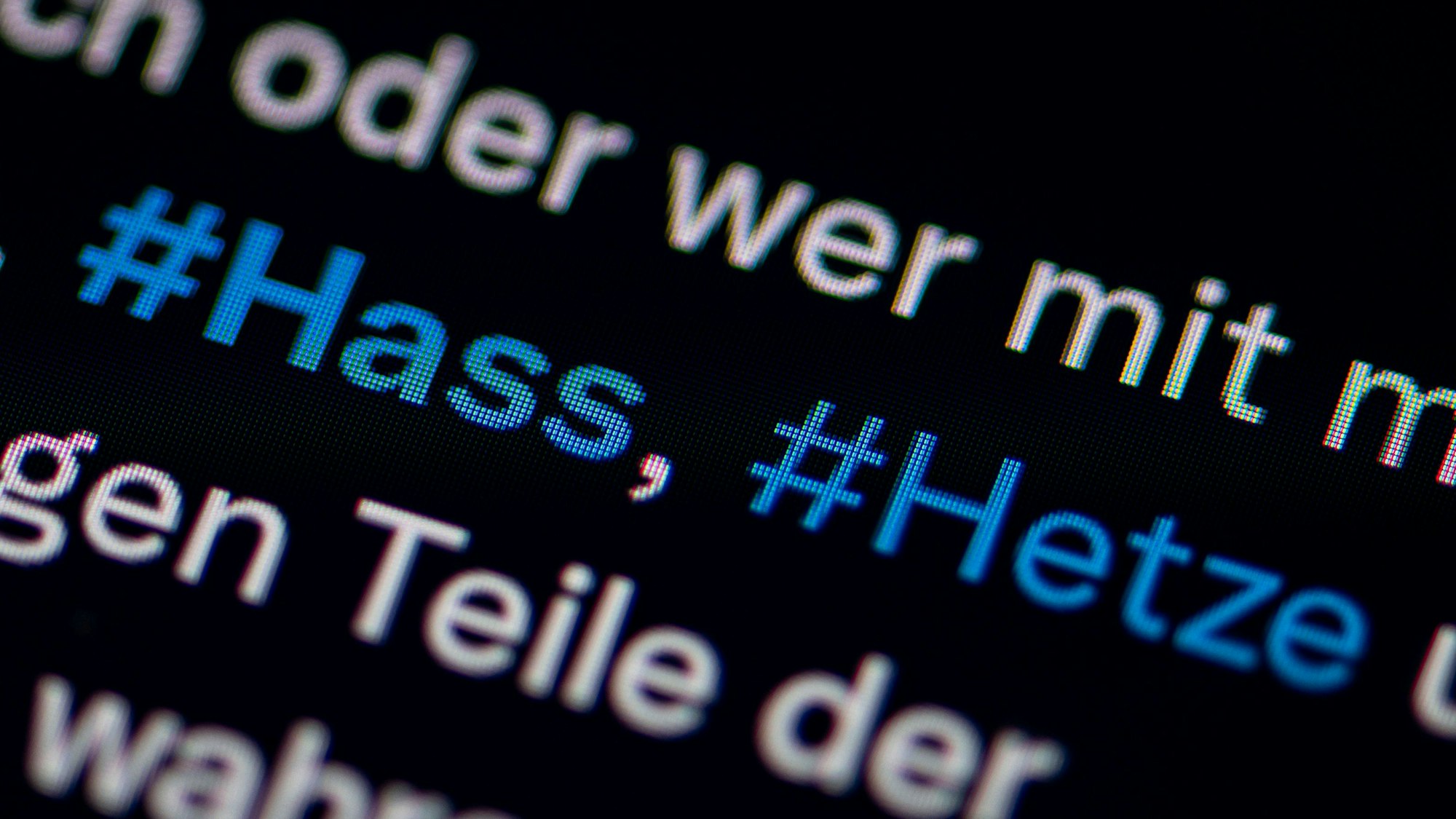 Auf dem Bildschirm eines Smartphones sieht man die Hashtags Hass und Hetze in einem Twitter-Post.