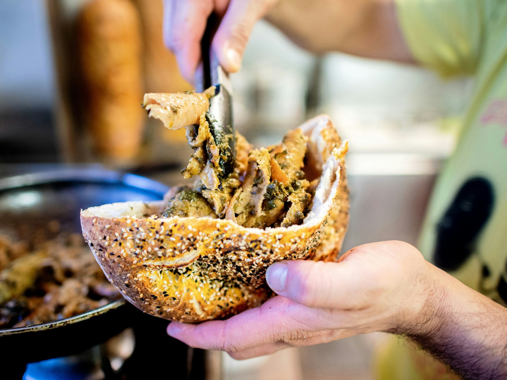 Der Imbissbesitzer Hani Alhay bereitet in der Küche in seinem Imbiss den Grünkohldöner mit Dönerfleisch und Grünkohl in der Pitatasche zu.