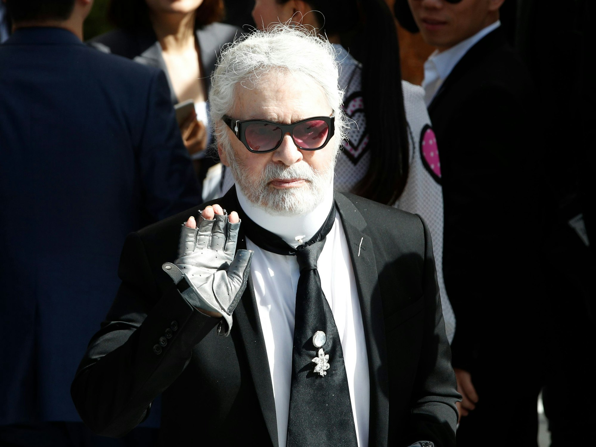 Karl Lagerfeld winkt auf der Paris Fashion Week 2018 in die Kamera.