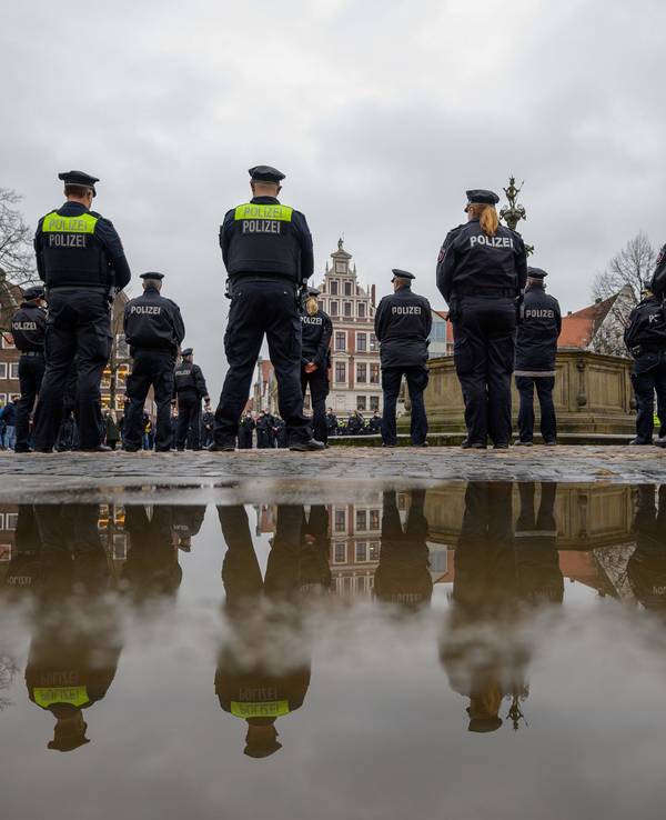 Polizisten stehen auf dem Marktplatz zusammen, um eine Schweigeminute für die in Rheinland-Pfalz getöteten Polizisten abzuhalten.