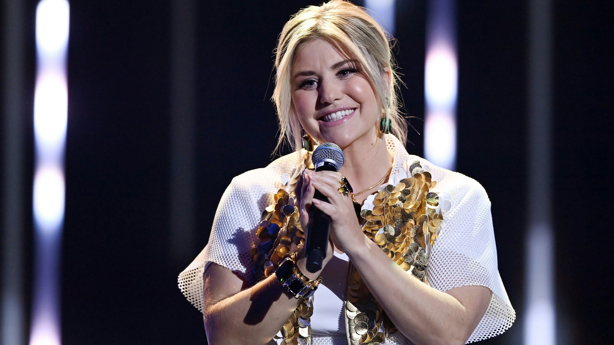 Die Schweizer Schlagersängerin Beatrice Egli steht während der Jose Carreras Gala auf der Bühne. Die Sängerin lächelt in die Kamera und hält ein Mikrofon vor dem Mund.