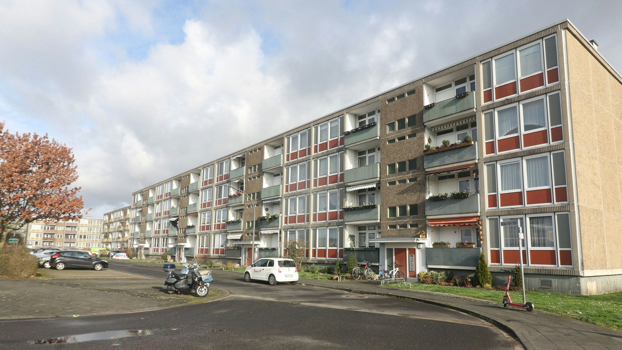 Ein Wohnblock mit Autostellplätzen davor.