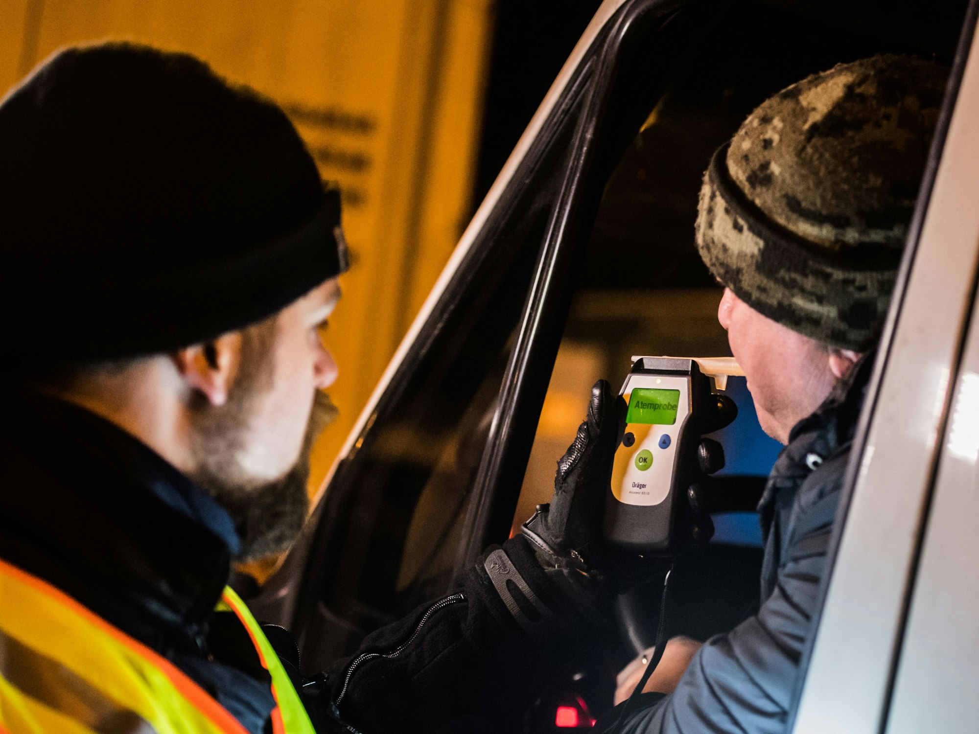 Ein Polizist kontrolliert einen LKW-Fahrer auf Alkoholgenuss.