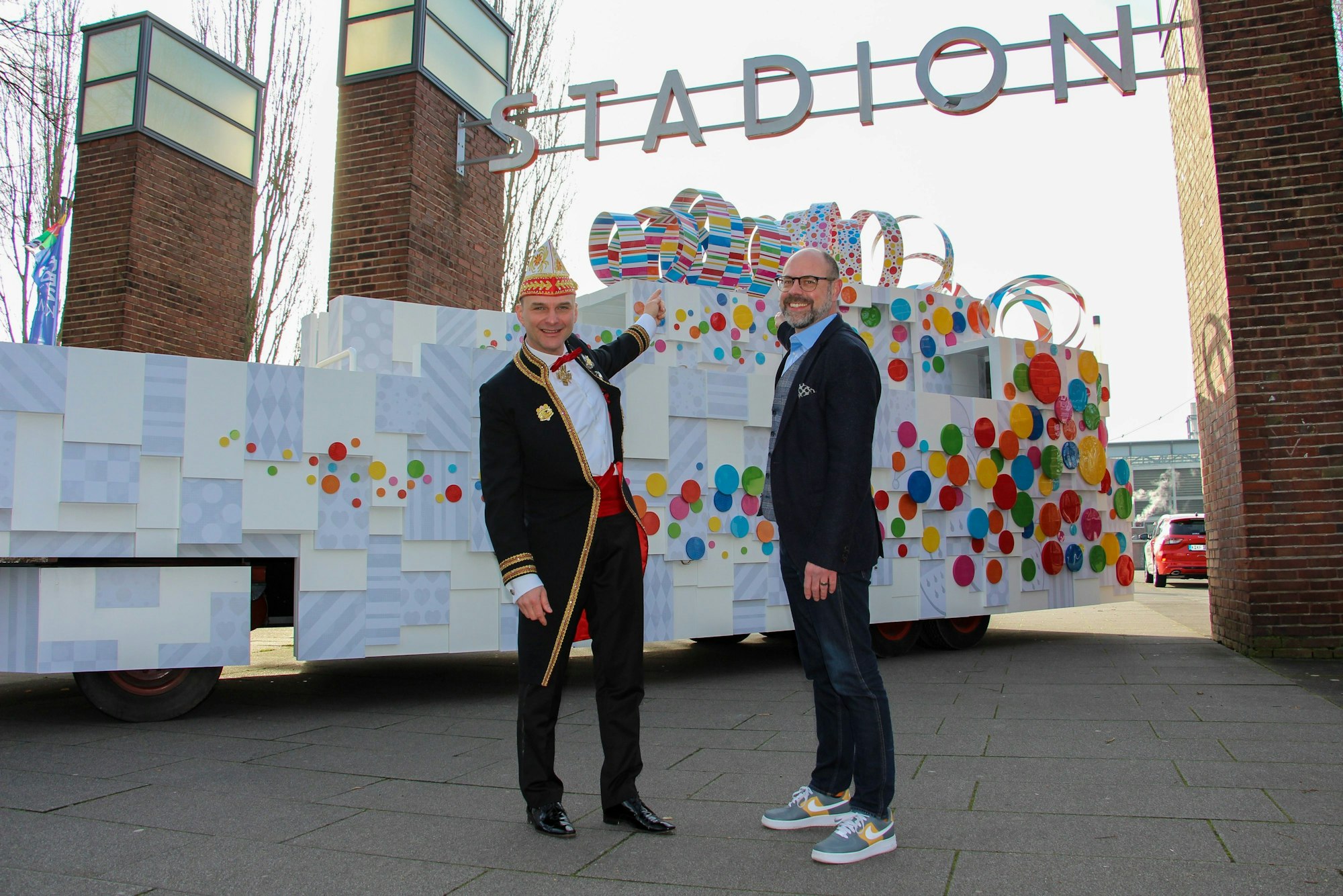 Holger Kirsch und Lutz Wingerath vor einem Karnevalswagen am Stadion in Köln.