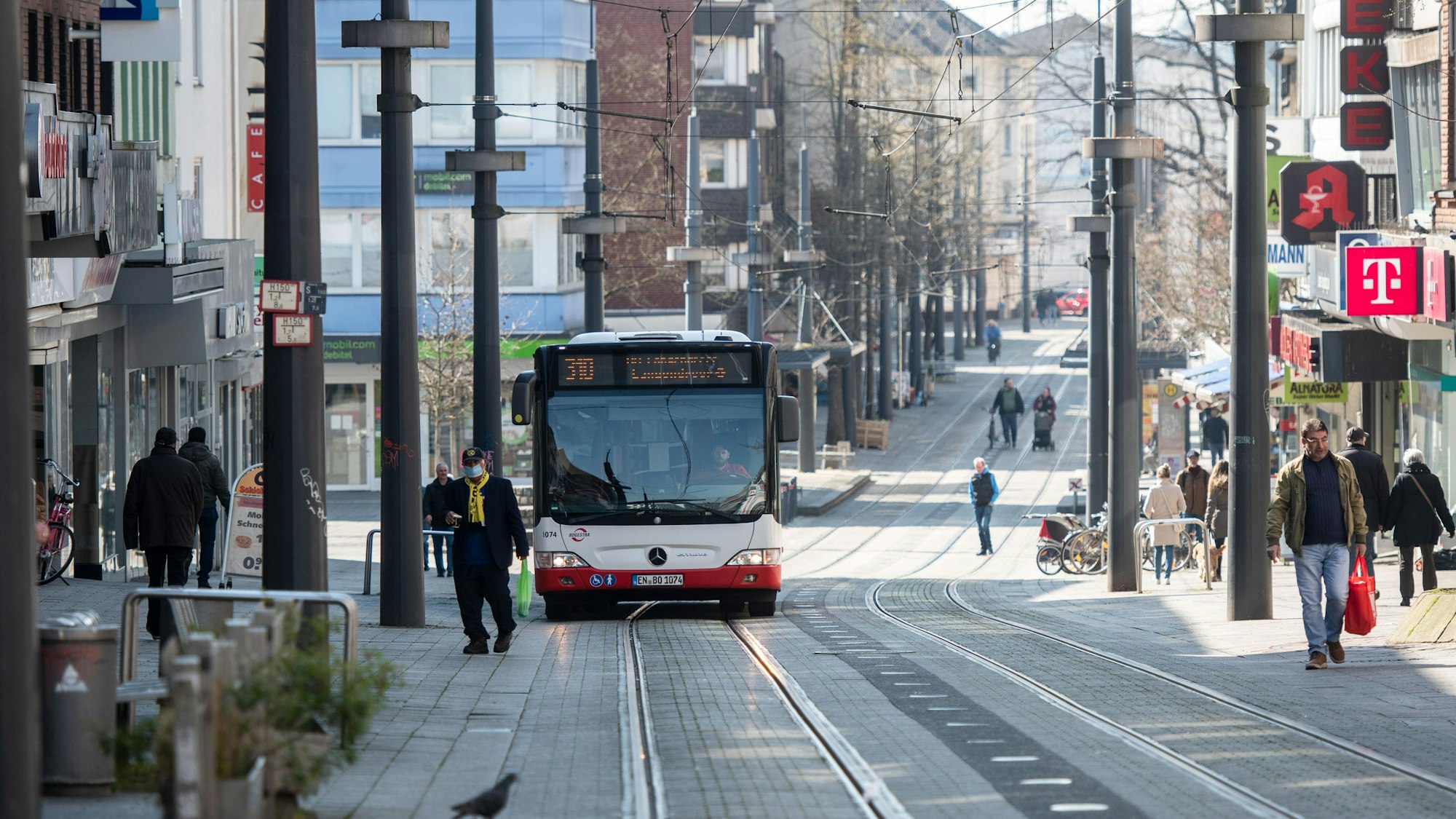 Bus fährt durch eine recht leere Fußgängerzone.