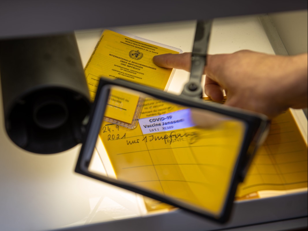Bei der Kriminalpolizeiinspektion liegen Impfpässe unter einer Lupe.