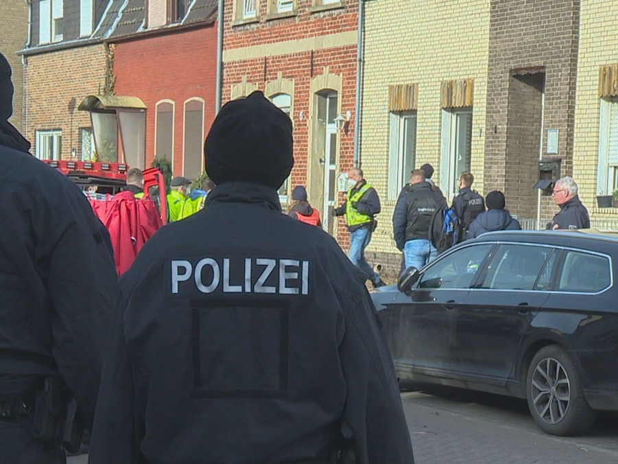 Einsatzkräfte der Polizei stehen bei einer Razzia vor einem Haus.