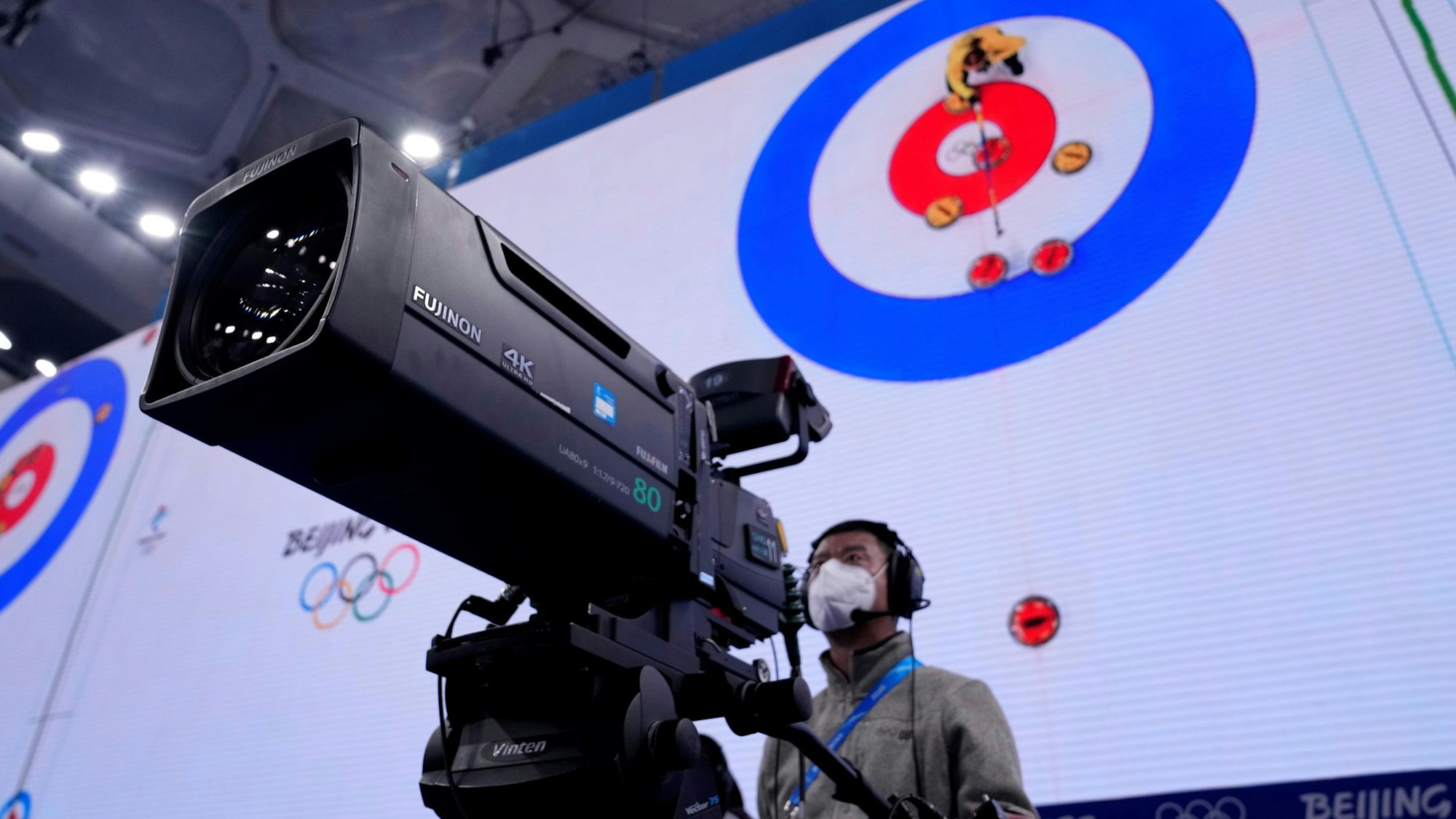 Ein Kameramann steht bei der Olympia-Übertragung der Curling-Halbfinals in Peking vor seinem Arbeitsgerät.