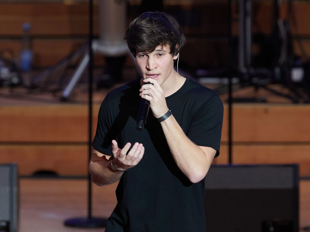 Wincent Weiss, Pop-Sänger, steht zum weltweit ersten Facebook-Weihnachtskonzert auf der Bühne in der Laeiszhalle. Dabei hält er sich ein Mikrofon vor den Mund und gestikuliert mit der rechten Hand.
