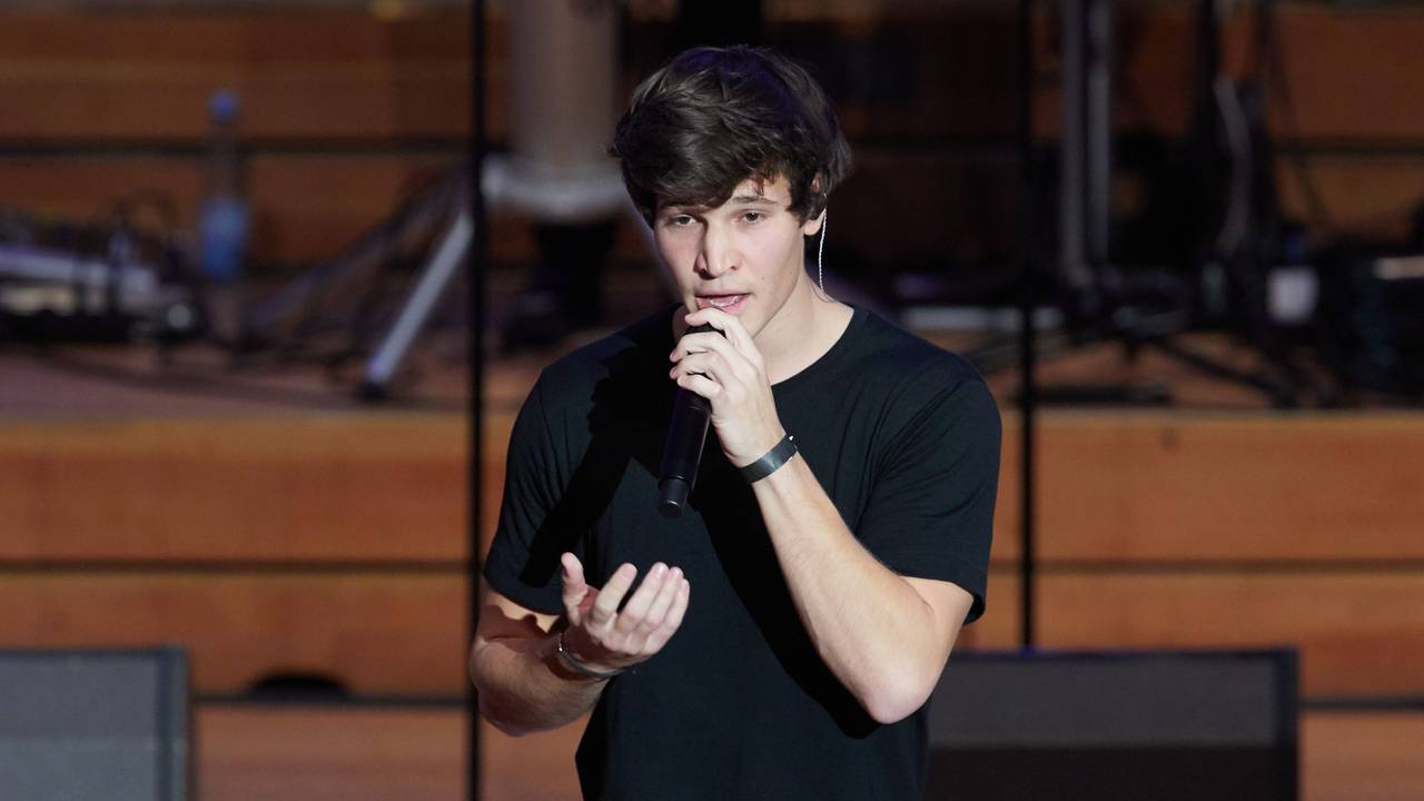 Wincent Weiss, Pop-Sänger, steht zum weltweit ersten Facebook-Weihnachtskonzert auf der Bühne in der Laeiszhalle. Dabei hält er sich ein Mikrofon vor den Mund und gestikuliert mit der rechten Hand.