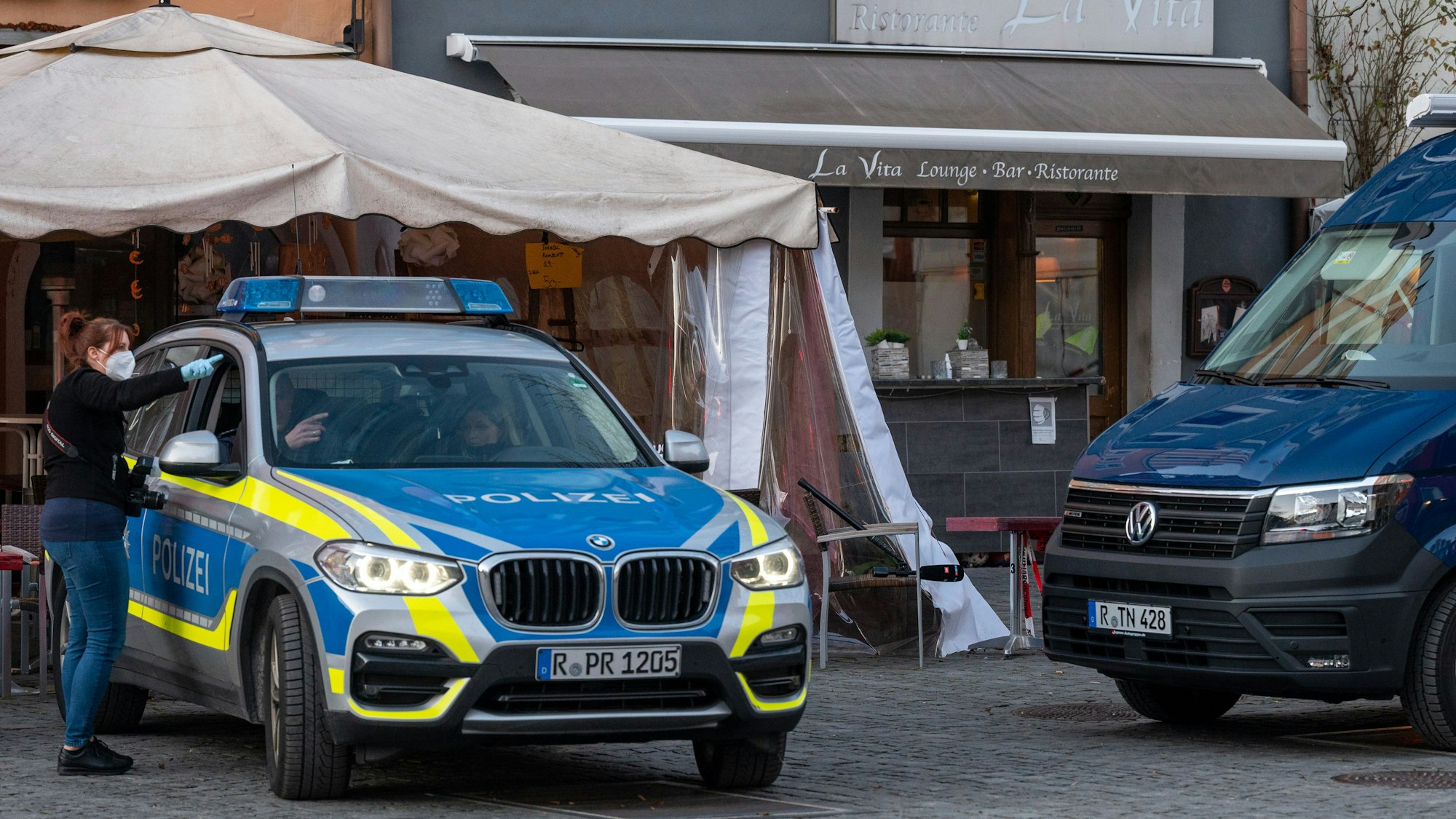 Polizeifahrzeuge stehen vor einem Lokal in der Innenstadt. Nach einem Restaurantbesuch ist ein 52-Jähriger möglicherweise an einer Vergiftung gestorben.