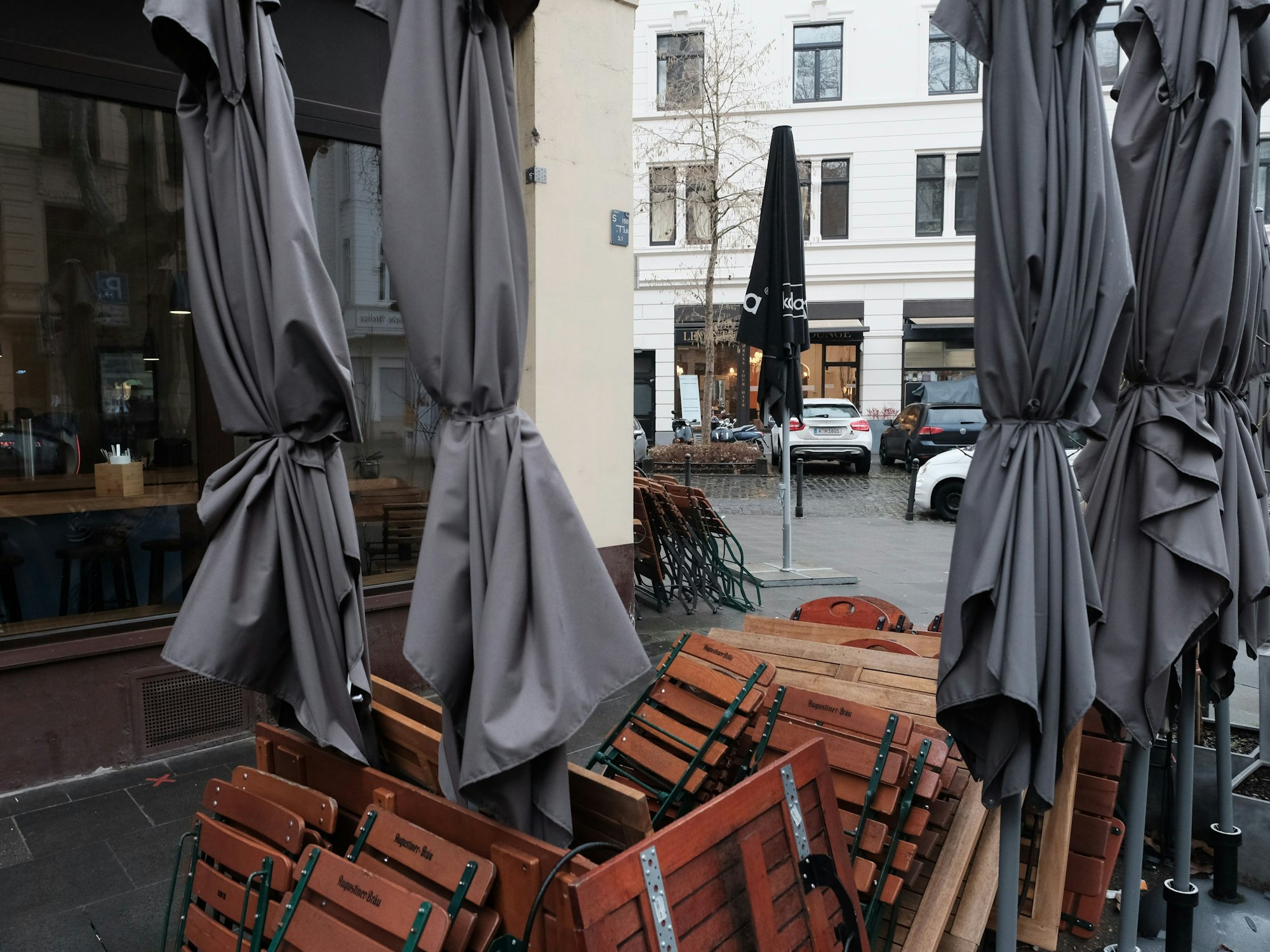 Zusammengeklappte Tische, Stühle und Schirme.