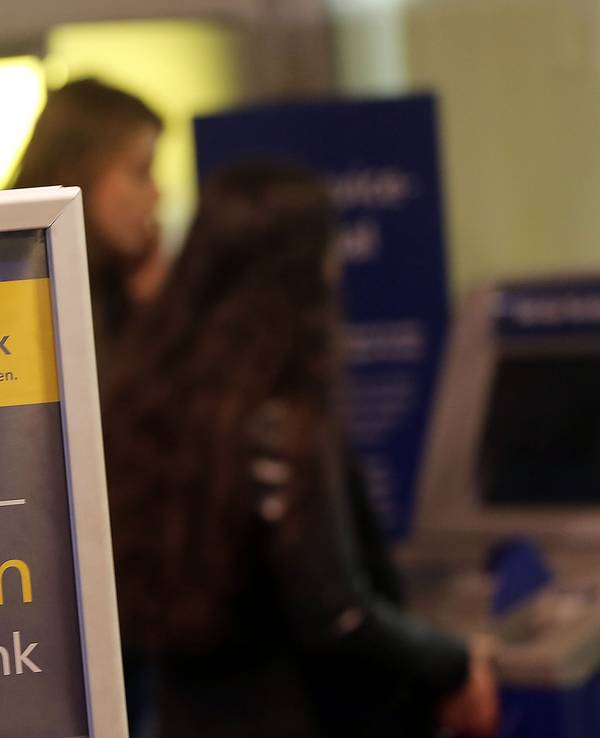 Kunden und Kundinnen der Postbank stehen am 27. Januar 2015 in Köln (Nordrhein-Westfalen) vor einer Filiale am Geldautomaten.