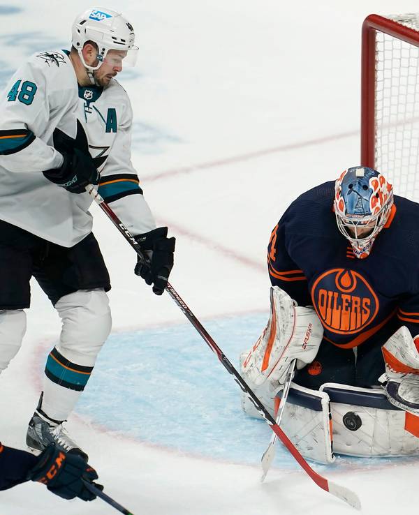 14.02.2022, USA, San Jose: Eishockey: NHL, San José Sharks - Edmonton Oilers, Hauptrunde, Hauptrunde-Partien, 117. Spieltag: Edmonton Oilers-Torwart Stuart Skinner (r) wehrt einen Schussversuch von San Jose Sharks-Center Tomas Hertl (M) ab.