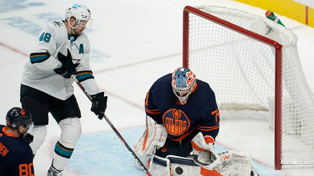 14.02.2022, USA, San Jose: Eishockey: NHL, San José Sharks - Edmonton Oilers, Hauptrunde, Hauptrunde-Partien, 117. Spieltag: Edmonton Oilers-Torwart Stuart Skinner (r) wehrt einen Schussversuch von San Jose Sharks-Center Tomas Hertl (M) ab.