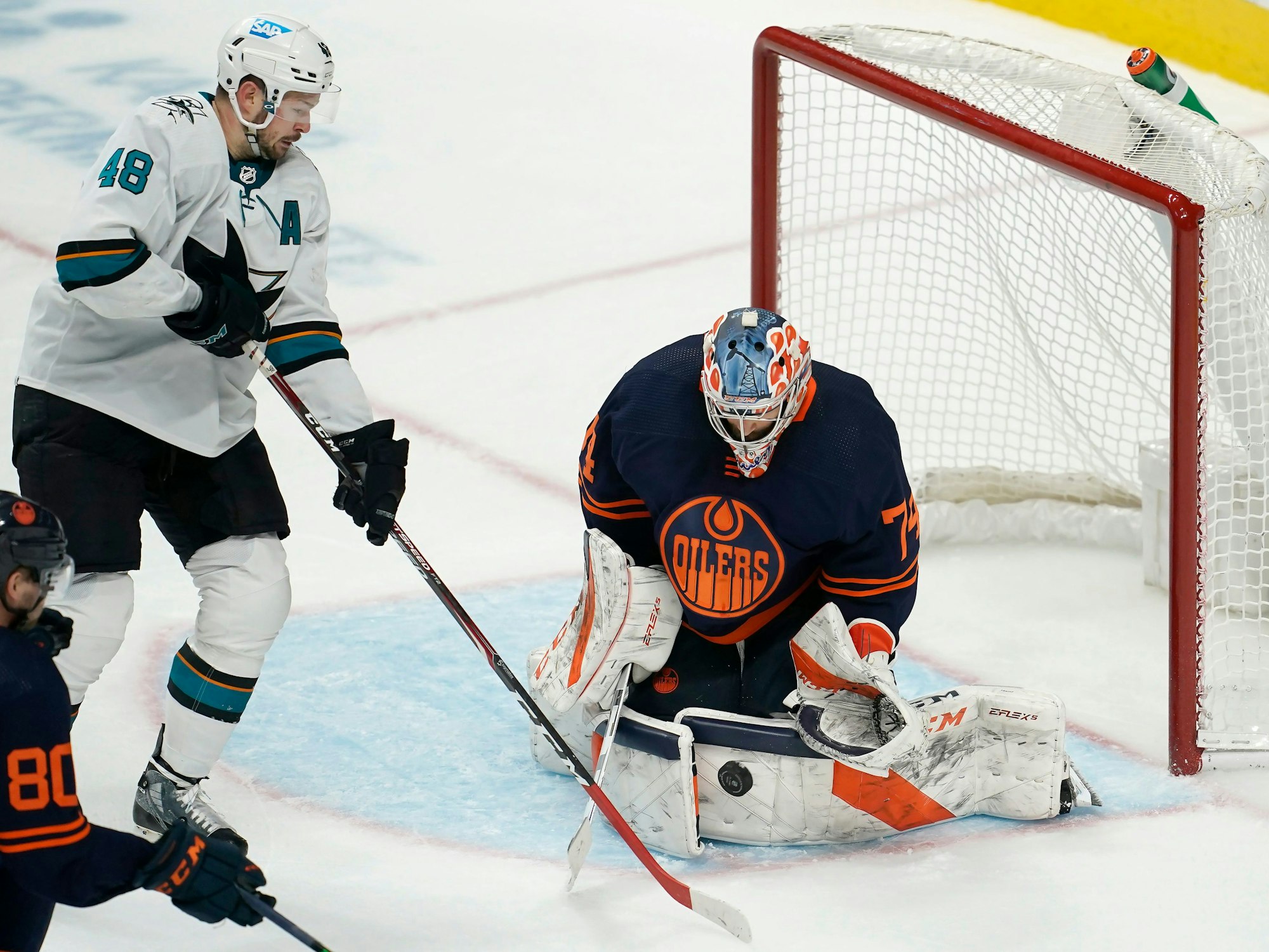 14.02.2022, USA, San Jose: Eishockey: NHL, San José Sharks - Edmonton Oilers, Hauptrunde, Hauptrunde-Partien, 117. Spieltag: Edmonton Oilers-Torwart Stuart Skinner (r) wehrt einen Schussversuch von San Jose Sharks-Center Tomas Hertl (M) ab.
