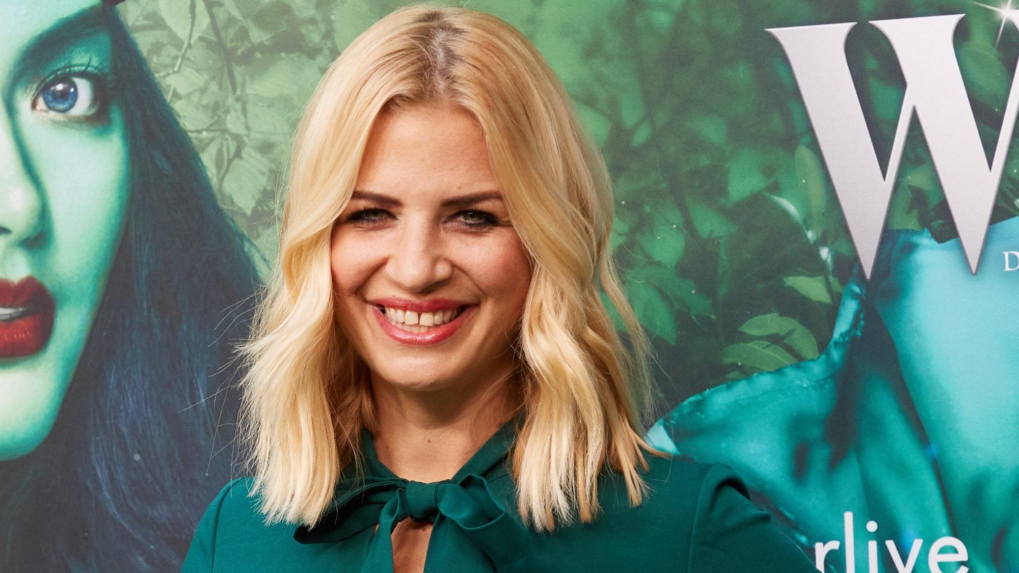 Susan Sideropoulos grinst auf dem roten Teppich in die Kamera.