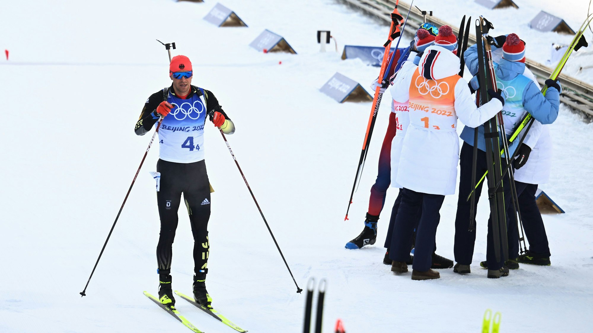 15.02.2022, China, Zhangjiakou: Olympia, Biathlon, Staffel 4 x 7,5 km, Herren, im Nationalen Biathlonzentrum, Philipp Nawrath (l) aus Deutschland steht im Ziel. Rechts jubelt das Team Norwegen. Foto: Hendrik Schmidt/dpa-Zentralbild/dpa +++ dpa-Bildfunk +++