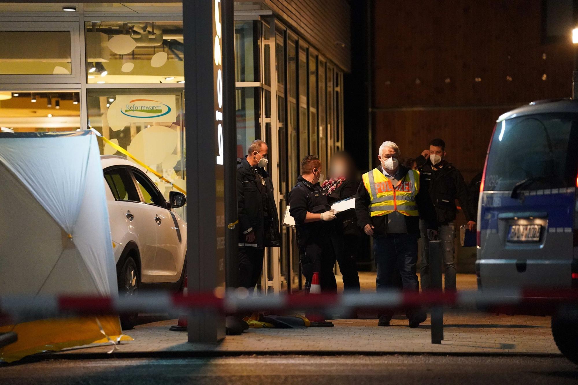 Polizisten stehen an einem Supermarkt.