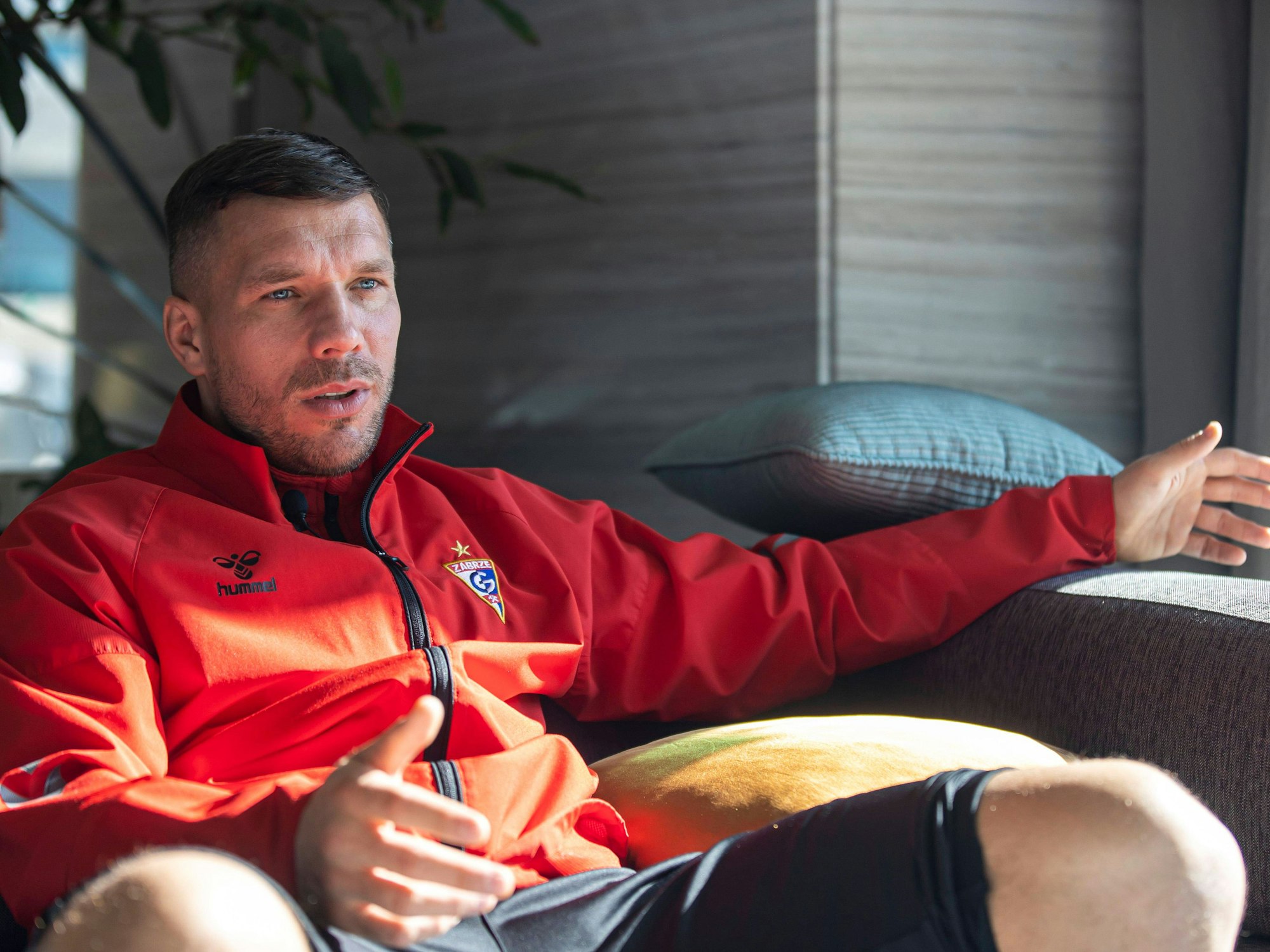 Lukas Podolski sitzt mit Trainingsjacke von Górnik Zabrze am 21. Januar 2022 bei einem Interview.