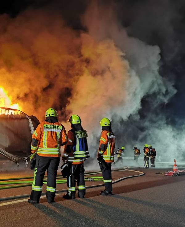 Feuerwehrleute vor einem brennenden Lkw auf der Autobahn.