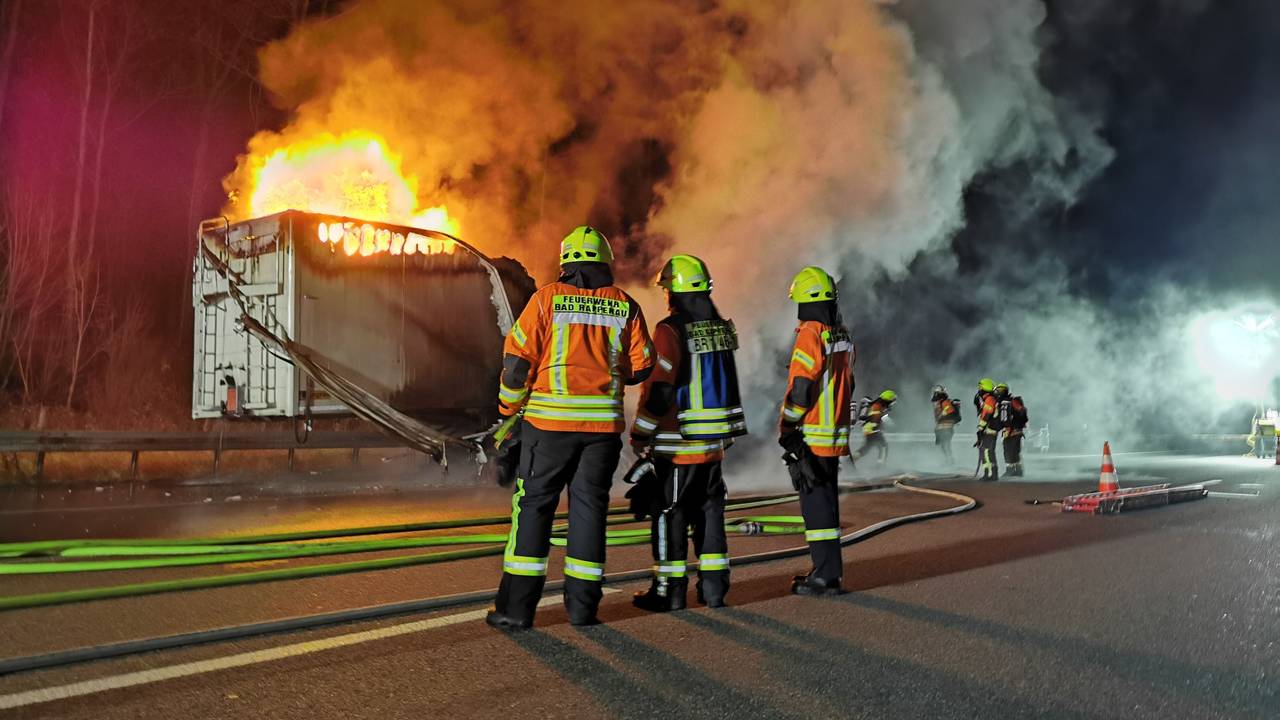 Feuerwehrleute vor einem brennenden Lkw auf der Autobahn.
