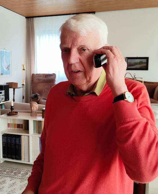 Rentner Herbert telefoniert in seinem Wohnzimmer.
