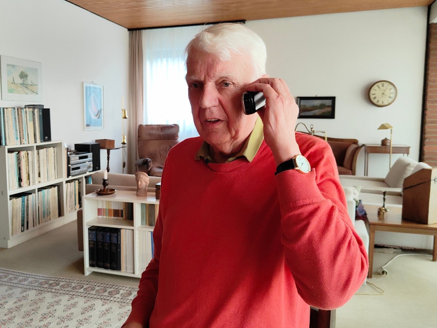 Rentner Herbert telefoniert in seinem Wohnzimmer.