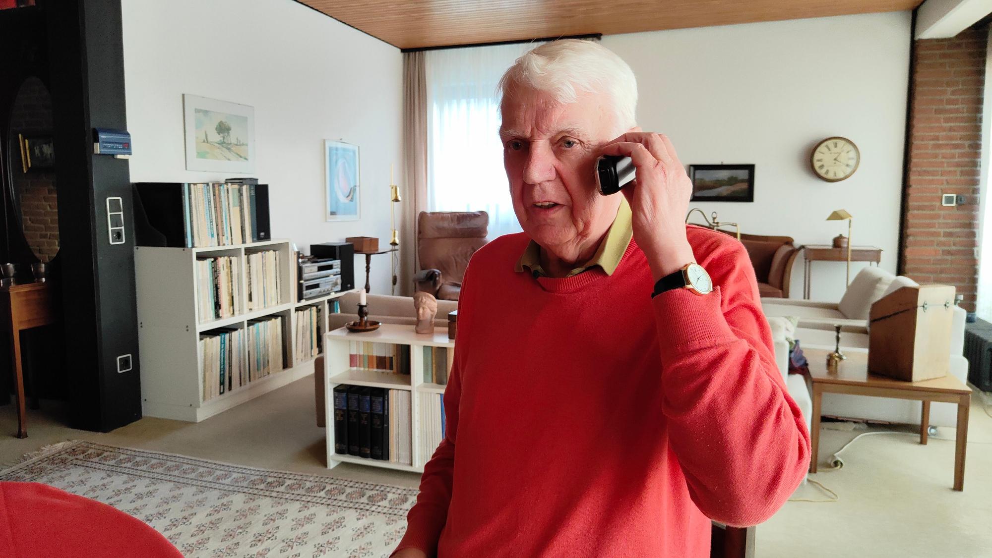 Rentner Herbert telefoniert in seinem Wohnzimmer.