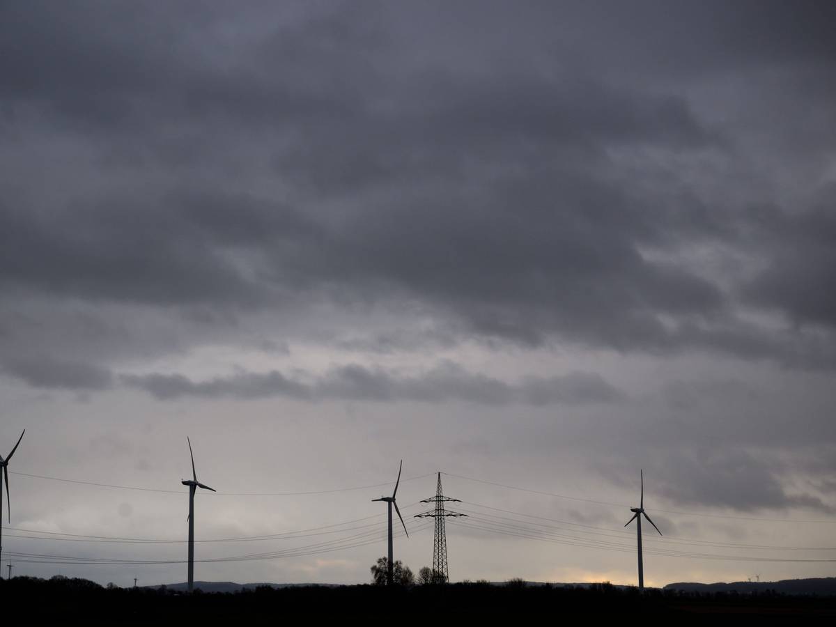 Dunkle Wolken ziehen über Felder mit Windrädern