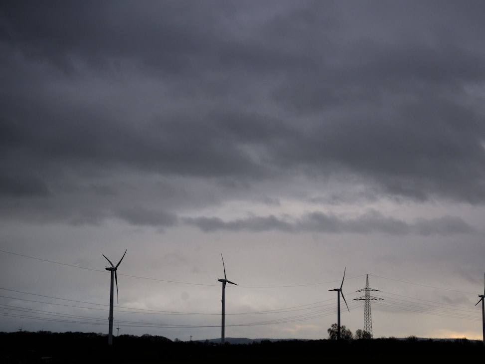 Dunkle Wolken ziehen über Felder mit Windrädern