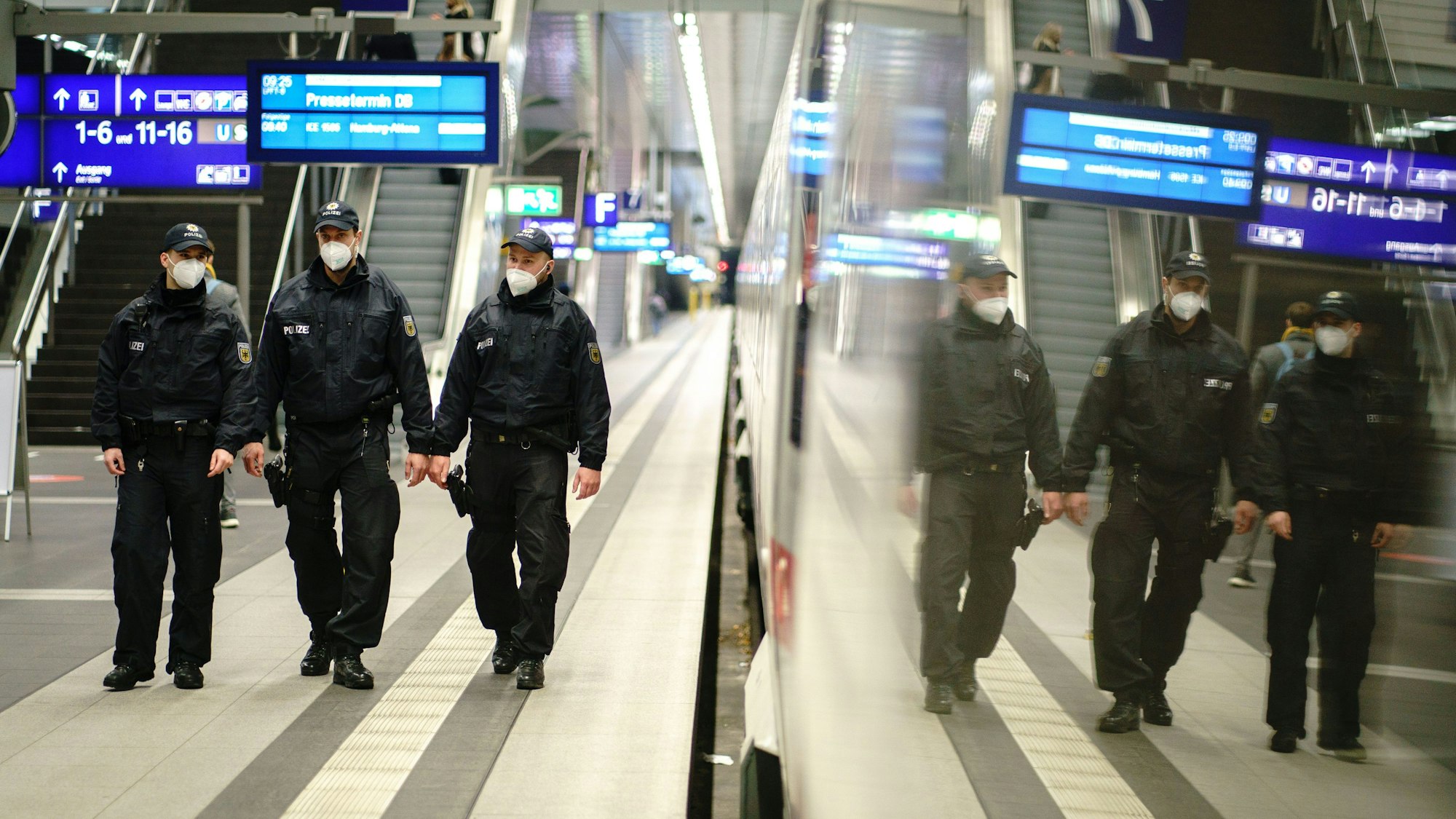 Beamte der Bundespolizei gehen durch einen Bahnhof.