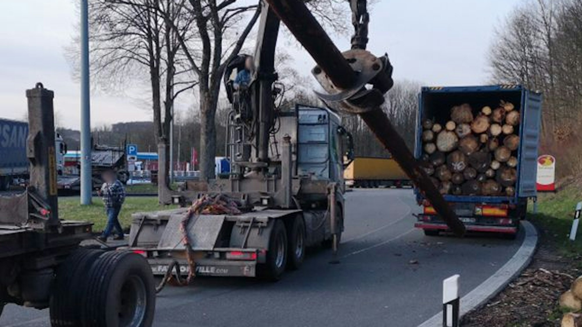 Ein Kran lädt einen Baumstamm aus einem Lkw.