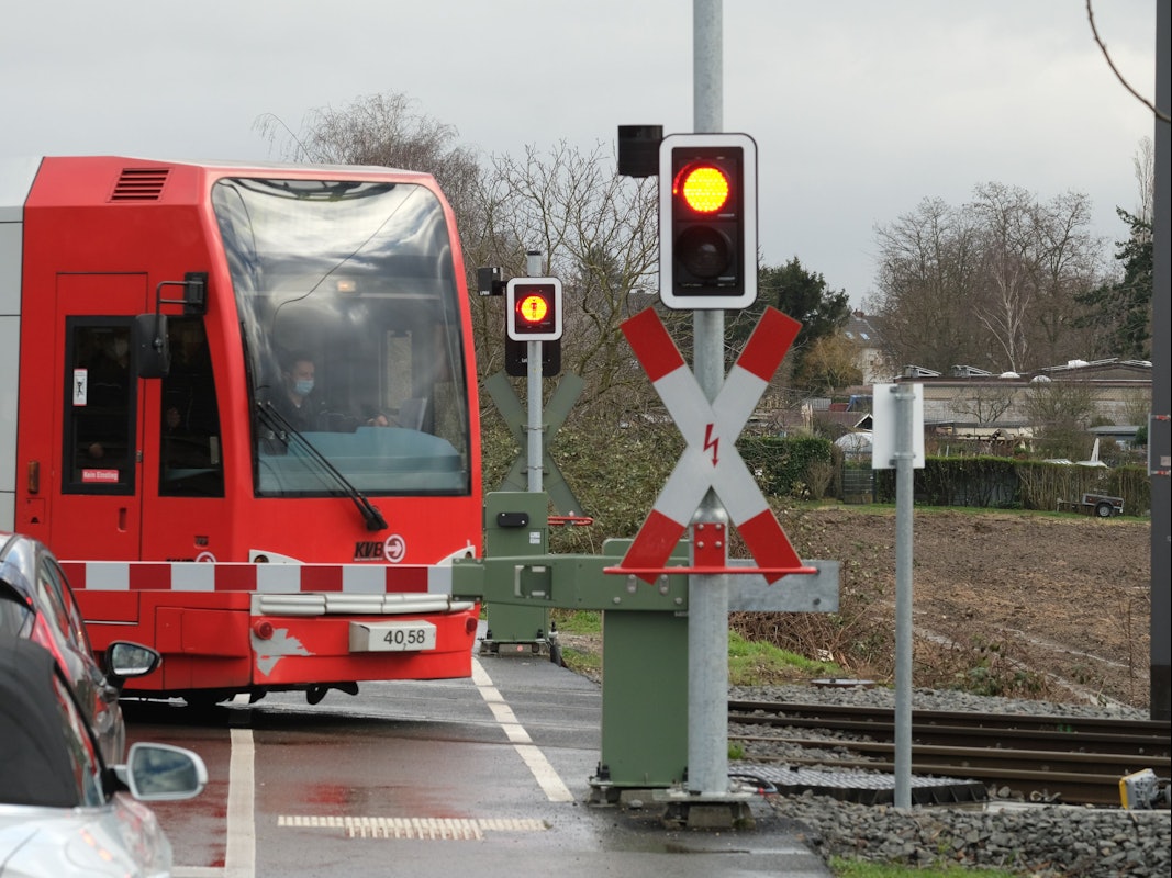 Eine Bahn der KVB passiert auf dem Weg zur Hauptwerkstatt Schienenfahrzeuge an einem Bahnübergang den Simonskaul.
