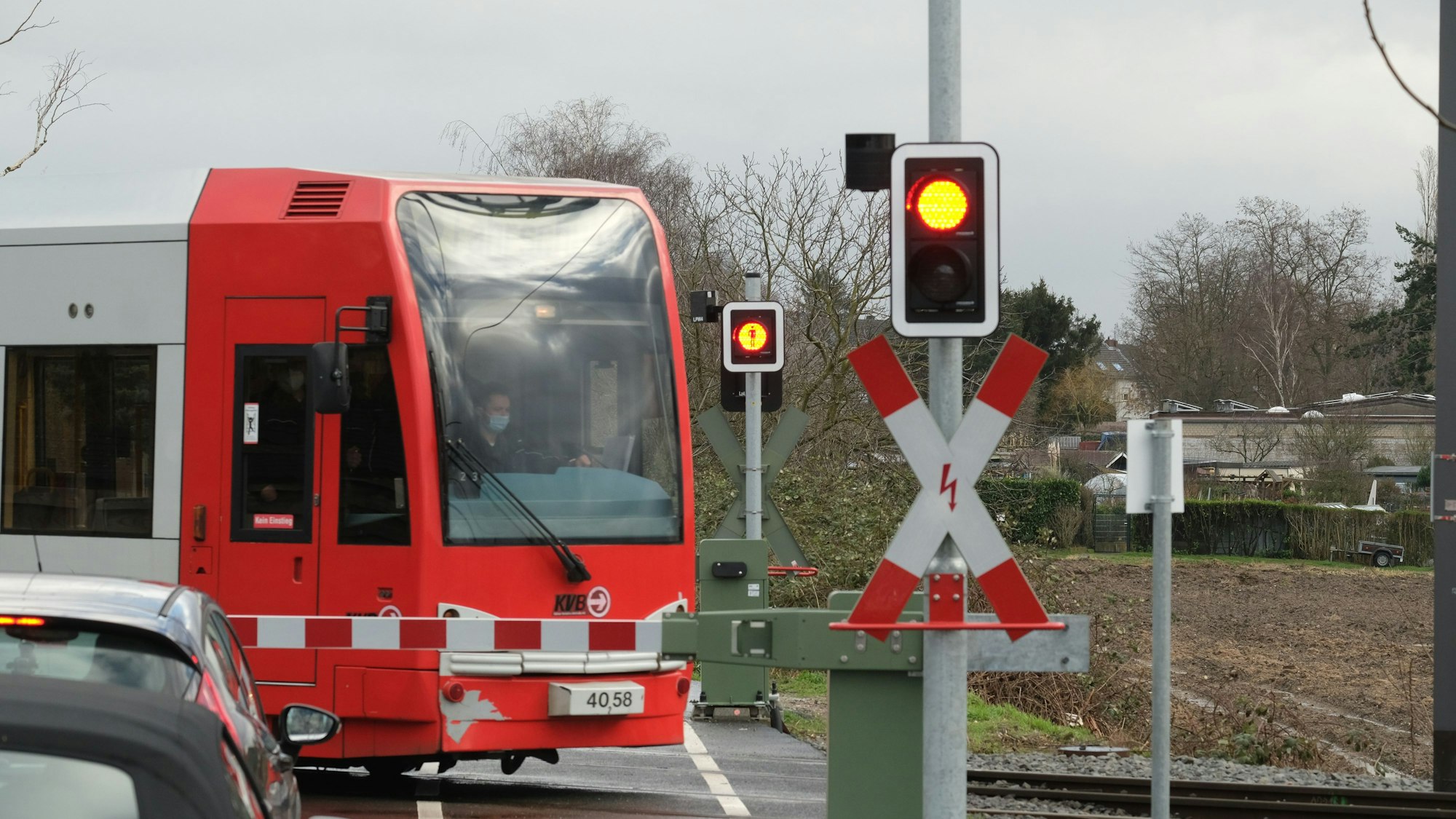 Eine Bahn der KVB passiert auf dem Weg zur Hauptwerkstatt Schienenfahrzeuge an einem Bahnübergang den Simonskaul.