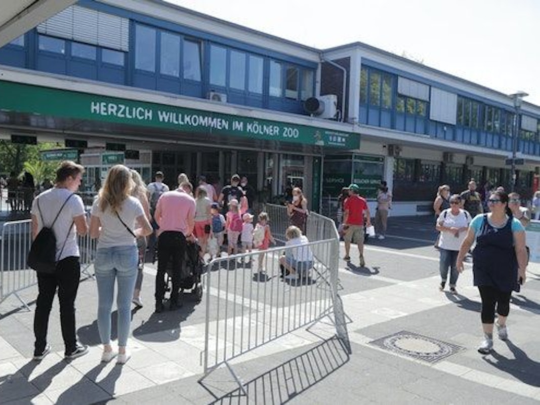 Menschen stehen in einer Warteschlange vor dem Kölner Zoo.