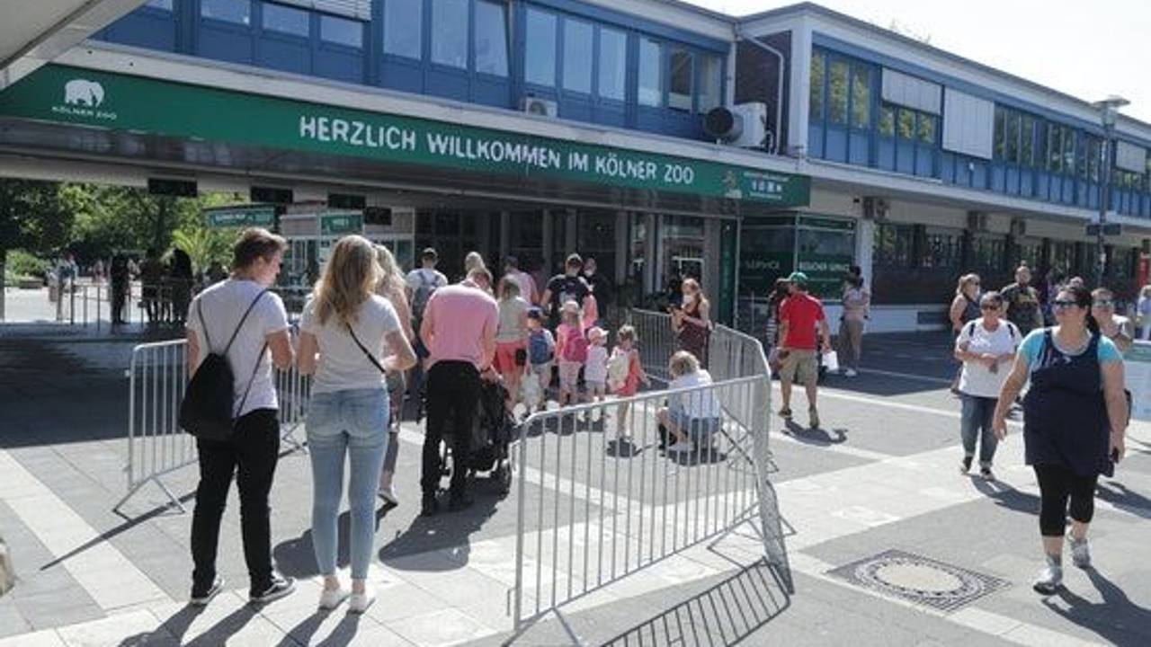Menschen stehen in einer Warteschlange vor dem Kölner Zoo.