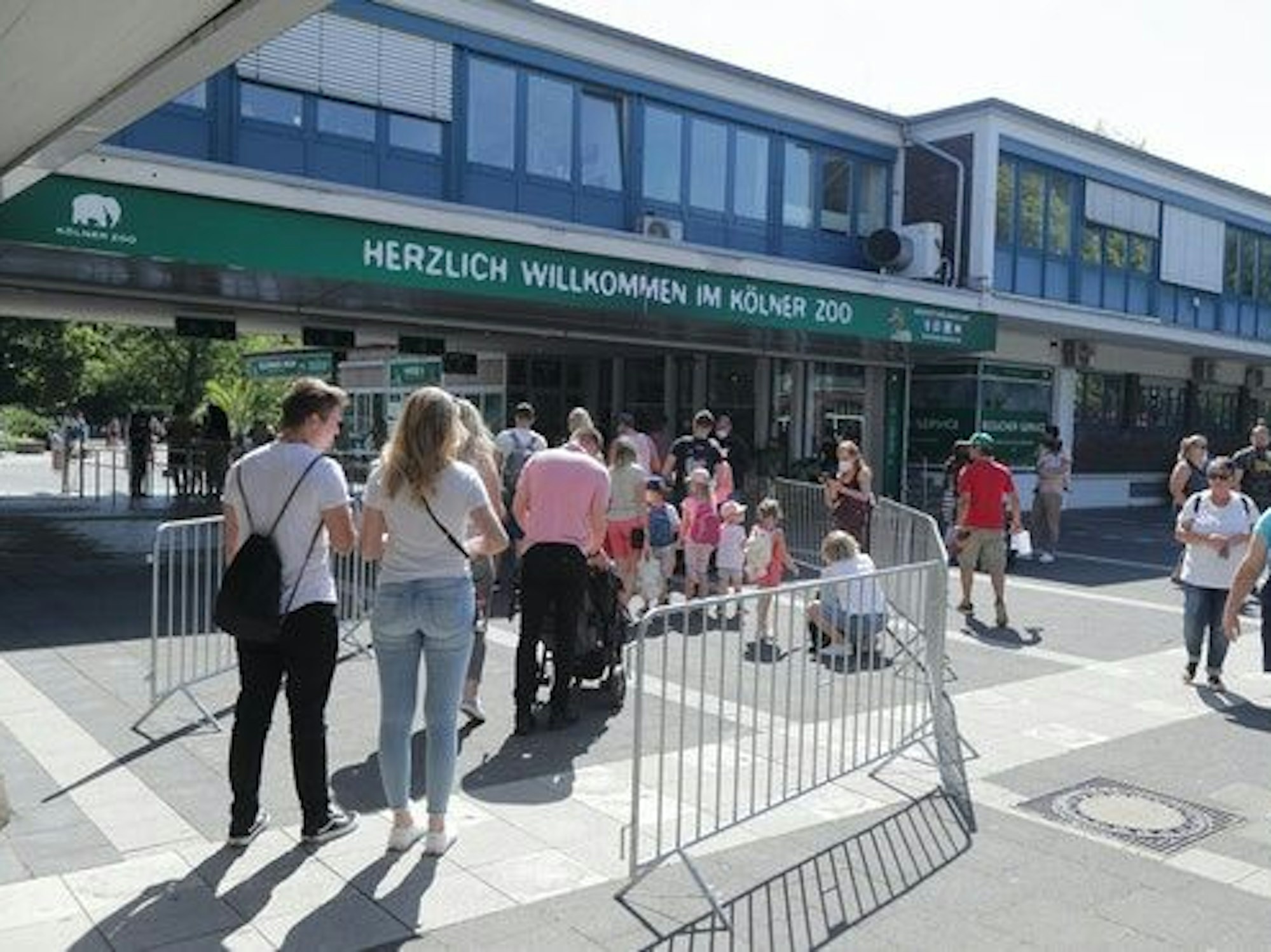 Menschen stehen in einer Warteschlange vor dem Kölner Zoo.